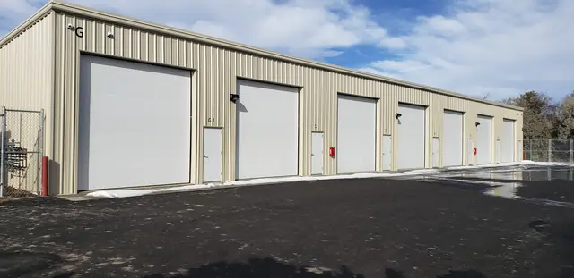 SYT Storage building with large white overhead doors and a man door next to each unit