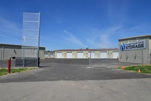 Computer-controlled entry gate and keypad at SYT Storage, with the Store Your Toys Storage sign beyond