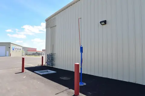 RV dump station at SYT Storage with a blue fresh-water riser and protective bollards beside a storage building